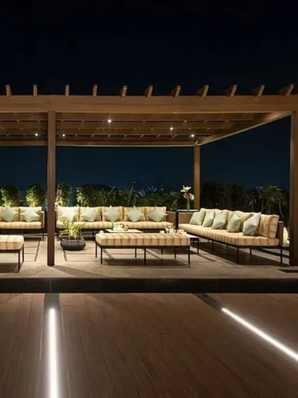 The same hotel terrace transforms at night. With integrated lighting in the flooring and under the pergola, the space becomes a sophisticated venue for evening gatherings.