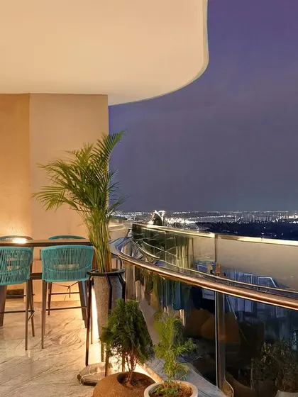 This balcony features a high-top table and chairs, creating a perfect spot for evening drinks or a morning coffee with a view. The design maximizes the potential of this outdoor space, making it a true extension of the home.