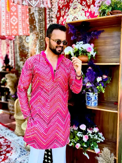 A candid shot smelling a flower against a vibrant pink and floral decor. It's the small, beautiful details at weddings that make them so special.