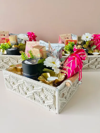 Our macrame trays offer a bohemian and stylish alternative to traditional boxes. This hamper is filled with goodies and decorated with a bright pink potli.