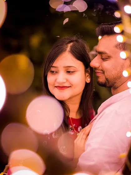 A sweet, candid interaction between a couple, with the bokeh from the fairy lights adding a touch of magic to this pre-wedding portrait.