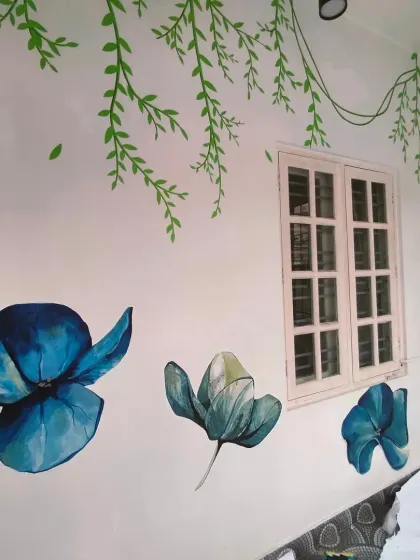 A serene floral mural for a home, with delicate green vines hanging from the ceiling and beautiful blue flowers blooming around a window.