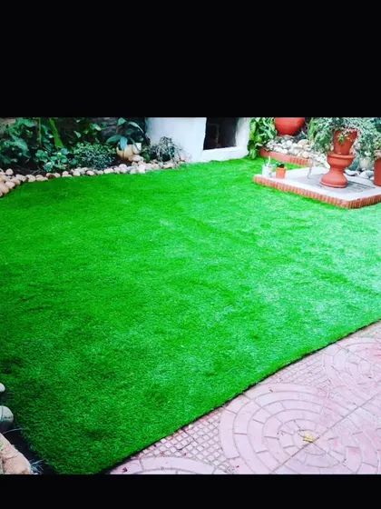 A backyard makeover combining artificial grass with a paved patio area. This creates distinct zones for different activities while keeping the space green.