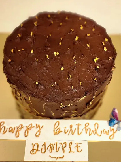 A tall and elegant chocolate strawberry cake for a 50th birthday. This cake is covered in a smooth dark chocolate ganache, sprinkled with edible gold flakes, and features a custom handwritten birthday message.