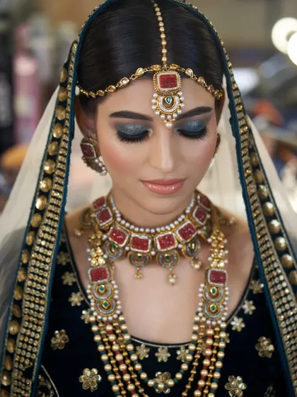 The full view of the teal smokey eye makeup. Paired with her deep green velvet outfit and red stone jewelry, this look is the epitome of regal elegance.