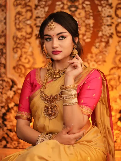 An elegant portrait of a model in a golden saree with a pink blouse. Her classic pose and the rich, traditional jewelry create a look of timeless South Indian beauty.
