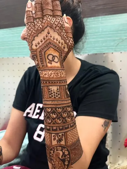 This engagement mehndi features a beautiful motif of interlocking rings on the forearm, surrounded by geometric and traditional patterns. It's a perfect blend of modern symbolism and classic art.