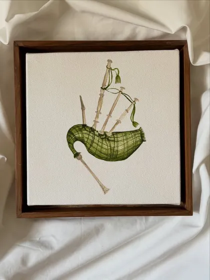 A detailed miniature painting of a set of bagpipes, showcasing the plaid pattern and intricate form of the instrument on a small canvas.