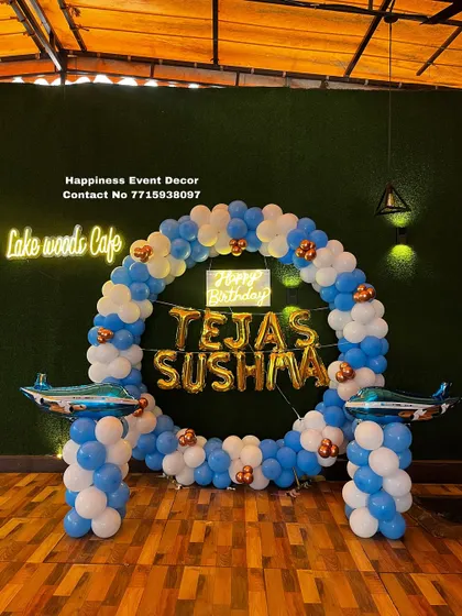 A balloon ring decoration for a birthday at a cafe. The blue and white balloon arch is accented with airplane props, perfect for a travel or aviation theme.