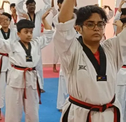 Students engaged in a warm-up exercise, stretching their arms and shoulders.