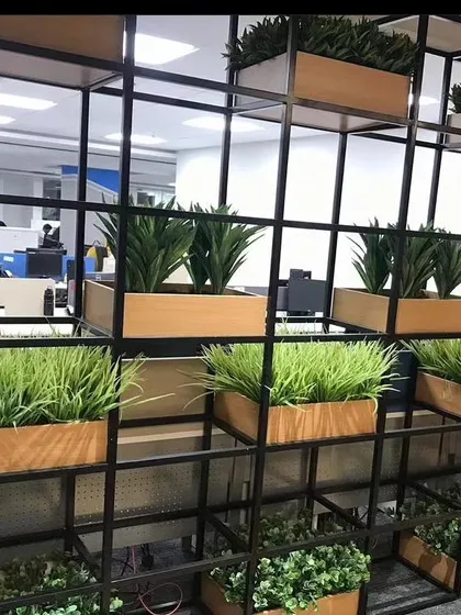 An office partition system made with a black metal frame and wooden planter boxes. I filled the boxes with different types of artificial grasses and plants to create a natural-looking divider.