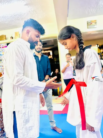 A young lady receives her red belt, a testament to her perseverance.