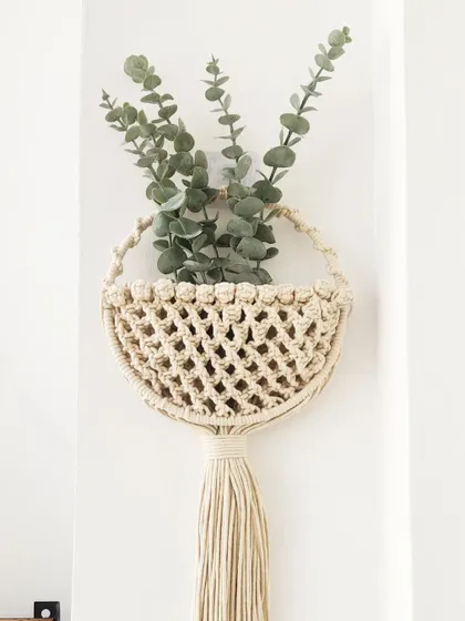 This half-moon macrame basket is perfect for hanging on a wall to hold dried flowers, mail, or other small items. It adds a touch of boho charm and practical storage to any room.