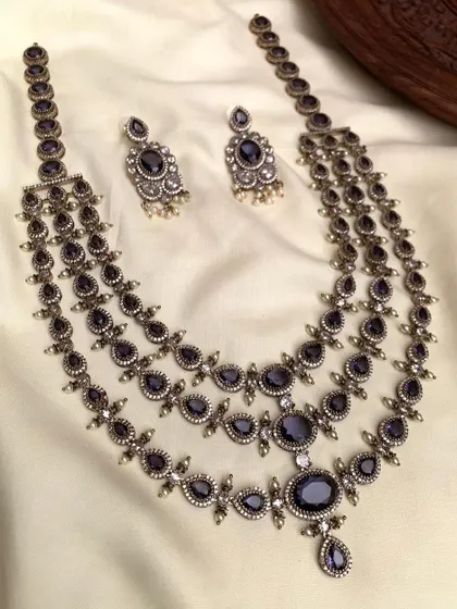 A three-layered necklace set with an antique silver finish. This long necklace is perfect for creating a layered, bohemian look and is available in green, blue, and red stones.