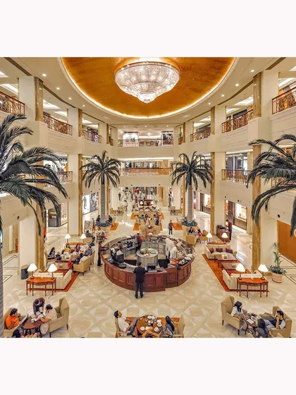 An interior view of the mall's grand atrium, showcasing its multi-level design, luxurious chandelier, and sophisticated ambiance. This image is designed to convey a high-end shopping experience.