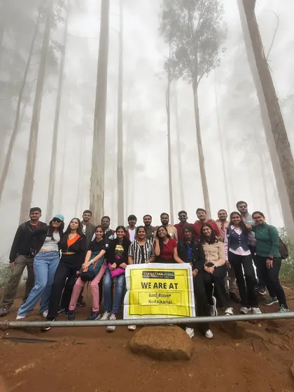 Our trek family posing with our banner in the misty Guna Caves area of Kodaikanal.