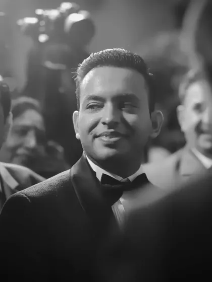 A candid black and white shot of the groom during his engagement party. The lighting and angle create a cinematic, handsome portrait.