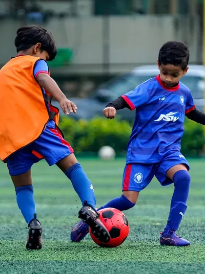 A young player skillfully dribbles past an opponent. Our training helps players develop the confidence and technique to take on defenders.
