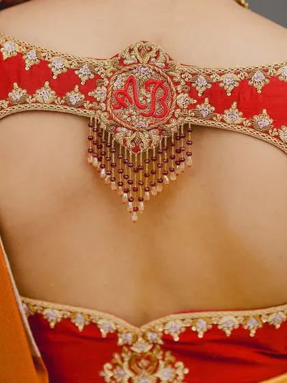 A close-up of Brunda's custom bridal blouse, featuring a beautiful cutout back with her and her partner's initials embroidered in a central motif.