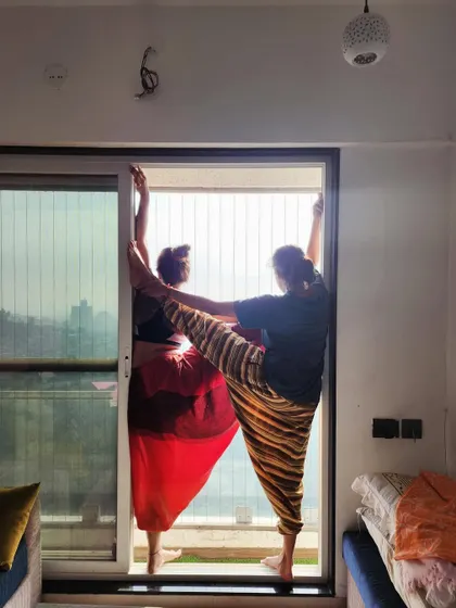 "Aaj kuch toofani karte hain." A playful moment of connection, supporting each other in a standing balance pose.