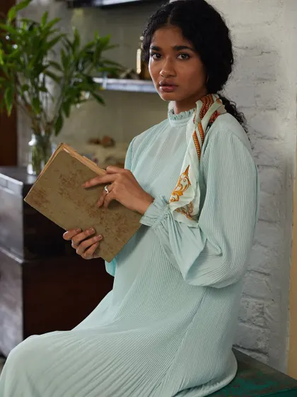 A narrative-driven shot for a modest fashion brand. The setting and the prop book create a story, suggesting a character who is thoughtful and well-read.