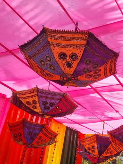 A view looking up at the decorative umbrellas and pink fabric ceiling, a key feature of the GIVA Holi event decor.