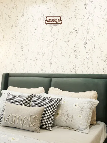 A close-up of the bed styling, showing the mix of different pillow patterns and the beautiful floral wallpaper. It’s a perfect example of a modern-bohemian look.