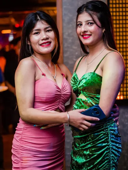 Two friends in vibrant pink and green dresses, lighting up the party.