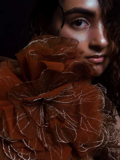 A detailed portrait showing the subtle, glossy finish on the lips and the highlight on the skin. The hair is styled with a natural, wet-curl texture.