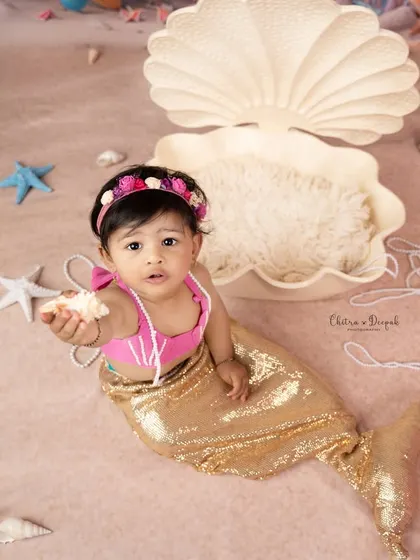 A charming shot of our little mermaid offering a seashell, set against a backdrop of pearls and starfish in our studio.