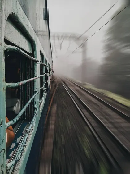 The view from a train window is blurred with speed, conveying the feeling of a fast-paced journey through the Indian landscape. This motion blur technique creates a dynamic and immersive travel photo.