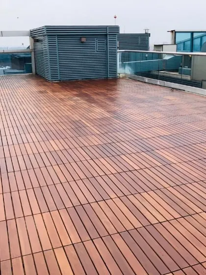 This wide shot shows the scale of a large rooftop terrace decked entirely in IPE wood tiles. The consistent grain and rich color elevate the entire outdoor area.