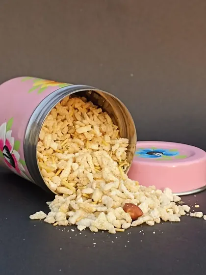 A hand-painted pink tin with snacks spilling out, part of a beautiful collection of painted vessels perfect for adding art to your home.