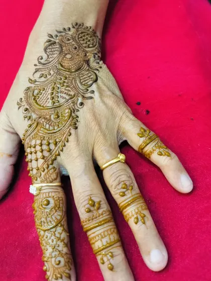 An elegant party design on the back of the hand, featuring a beautiful peacock and intricate finger details.