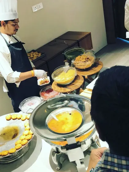 A live chaat counter is always the center of attention. Here, guests are gathered around our station, enjoying freshly prepared chaat during a corporate event, making for a lively and interactive dining experience.
