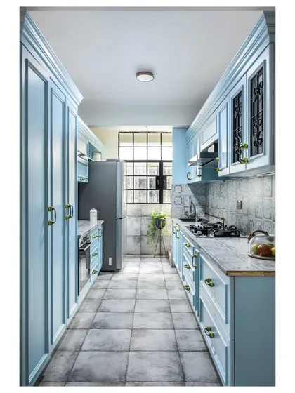 This galley kitchen is one of our most-loved designs. The powder blue cabinets, patterned floor tiles, and custom wrought-iron details on the upper cabinets create a bright, charming, and highly functional space.