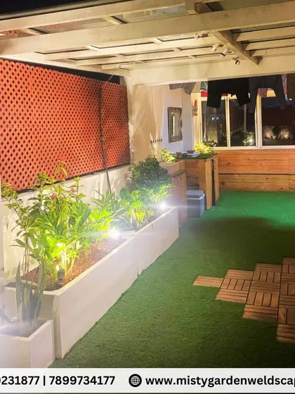 The combination of an artificial lawn, WPC decking, and illuminated planters creates a cozy and low-maintenance green retreat perfect for city living.
