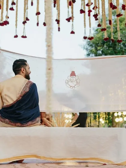 A traditional Hindu wedding ritual, the 'antarpat', held under a canopy of hanging red and white flowers.