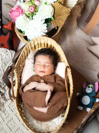 An overhead view of the sleeping newborn in a basket, surrounded by vintage props.