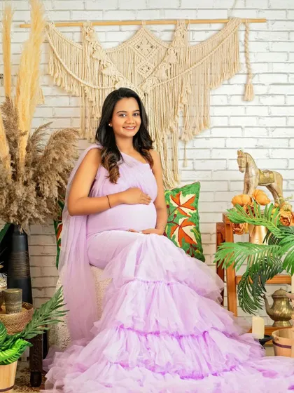 A smiling portrait of the mom-to-be, seated comfortably in our boho setup. The textures of the macrame and plants add so much depth.