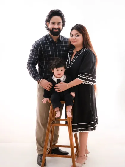 A dapper little gentleman and his parents. This classic family portrait on a high stool showcases the family's style against a clean white background.