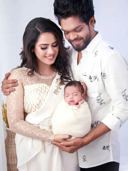 The complete family looks so serene in this newborn shoot. The white frill saree provides a pure and elegant look for the new mother.