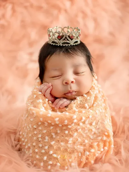 A classic newborn portrait of a sleeping baby girl, swaddled snugly and wearing a tiny, delicate crown. My newborn sessions are always handled with the utmost care and safety for your little one.