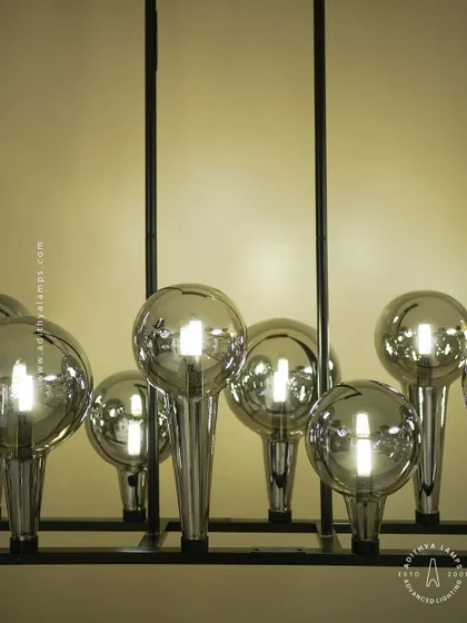 A playful yet chic linear chandelier featuring a series of chrome-finished glass bubbles. The highly reflective surface and modern design make it a striking addition to a kitchen island or a contemporary dining space.