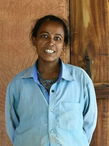 Portrait of Rupa, one of our most enthusiastic women masons, standing proudly in front of a wooden door set in an earthen wall she helped build.