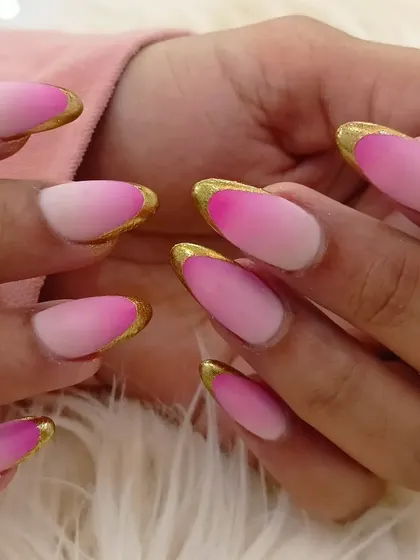 A close-up of the almond-shaped nails with a matte pink ombré and gold chrome French tip.
