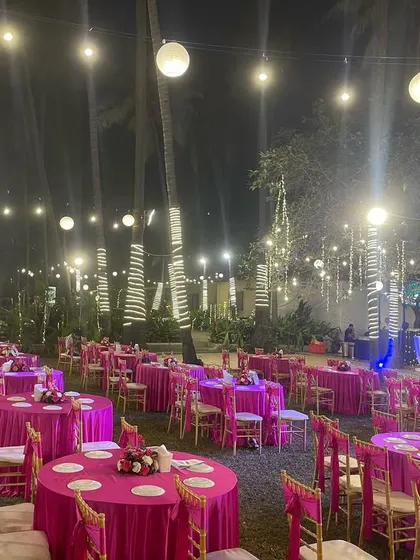 A vibrant pink-themed seating arrangement for an outdoor reception. The bold color choice for the tablecloths makes the entire venue pop, especially at night under the lights.