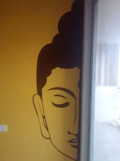 A creative placement of a large Buddha face decal, partially revealed from behind a sliding door on a warm yellow wall.
