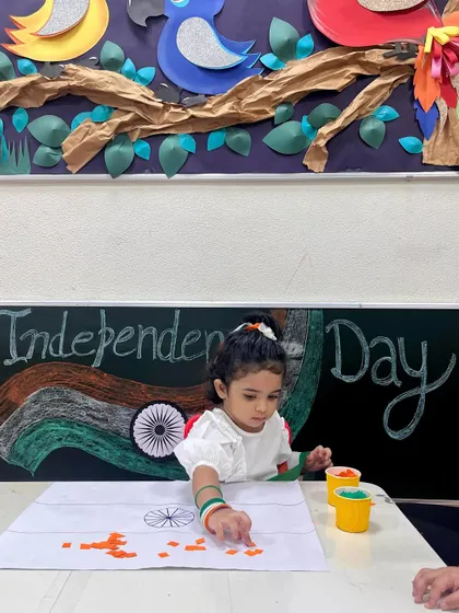 Surrounded by festive decorations, a child creates her flag. Our classroom environment is always decorated to reflect the theme or festival we are celebrating, making it more immersive.