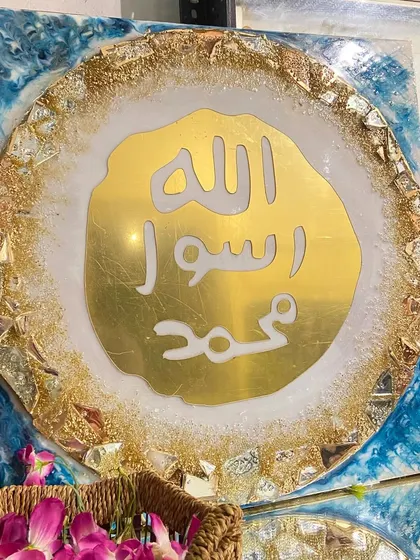 This luxury wall art features the Mohr e Nabuwat, or the Seal of Prophet Muhammad (PBUH). The design is set in gold and turquoise resin with a geode-like textured border, perfect for an exquisite living room.